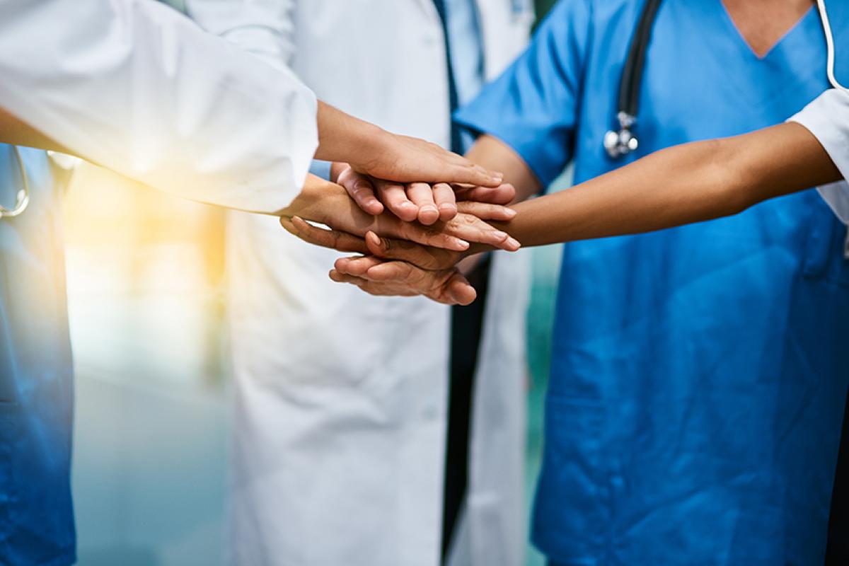 stock photo of medical professionals standing in a group with their hands overlapping each others in the center