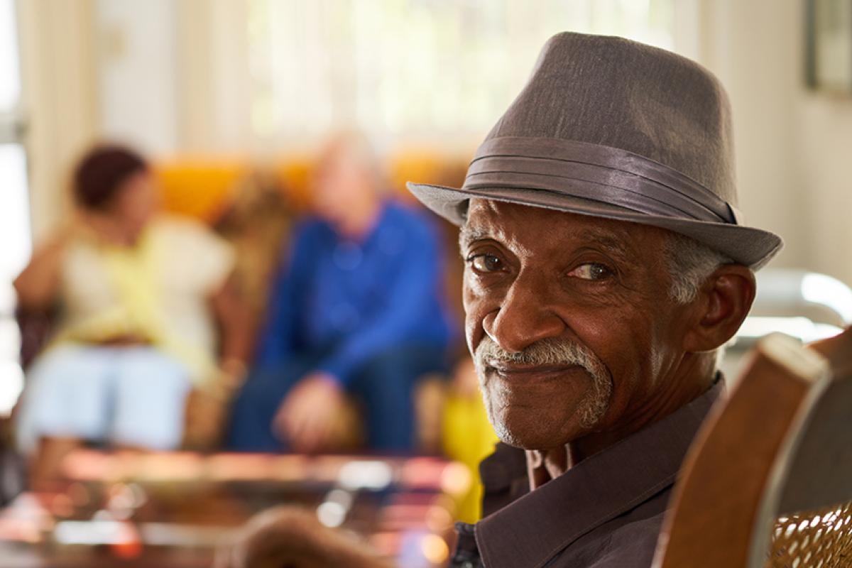 stock photo showing an older man in the forefront with two people sitting in the background 