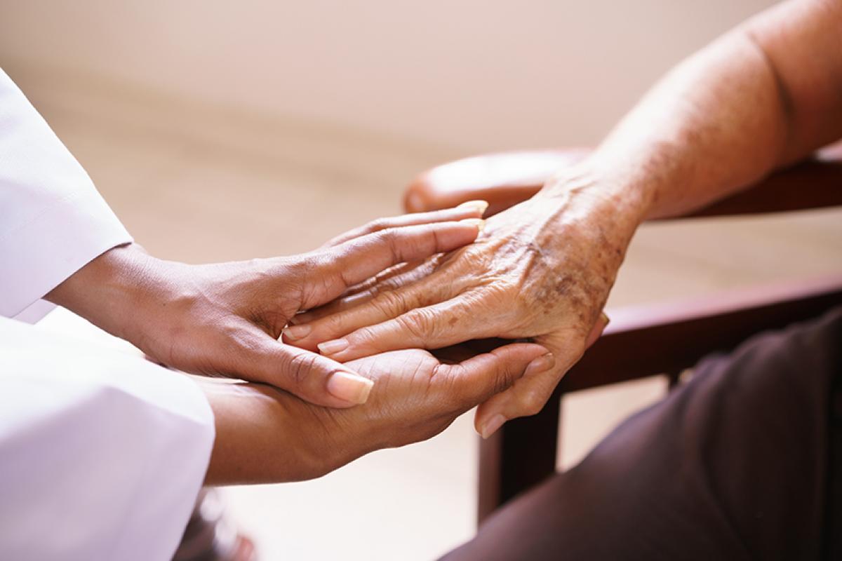 photo of a doctor holding the hand of an older patient