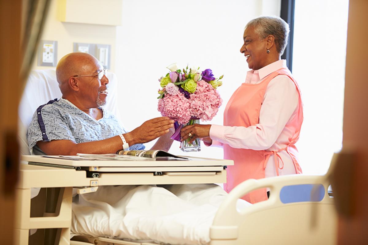 photo showing a female volunteer delivering flowers to a male patient