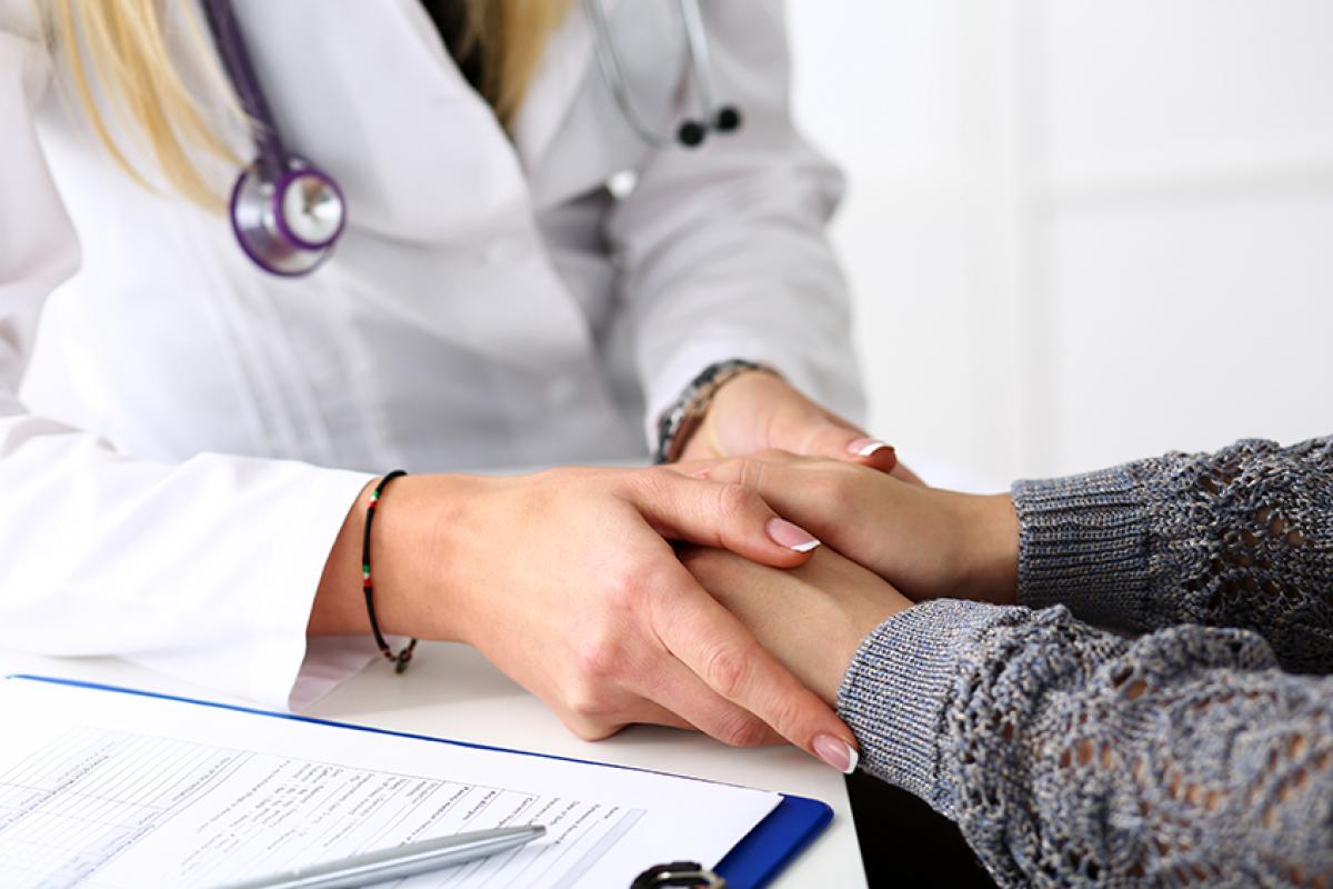 stock photo of a female doctor holding the hands of a female patient