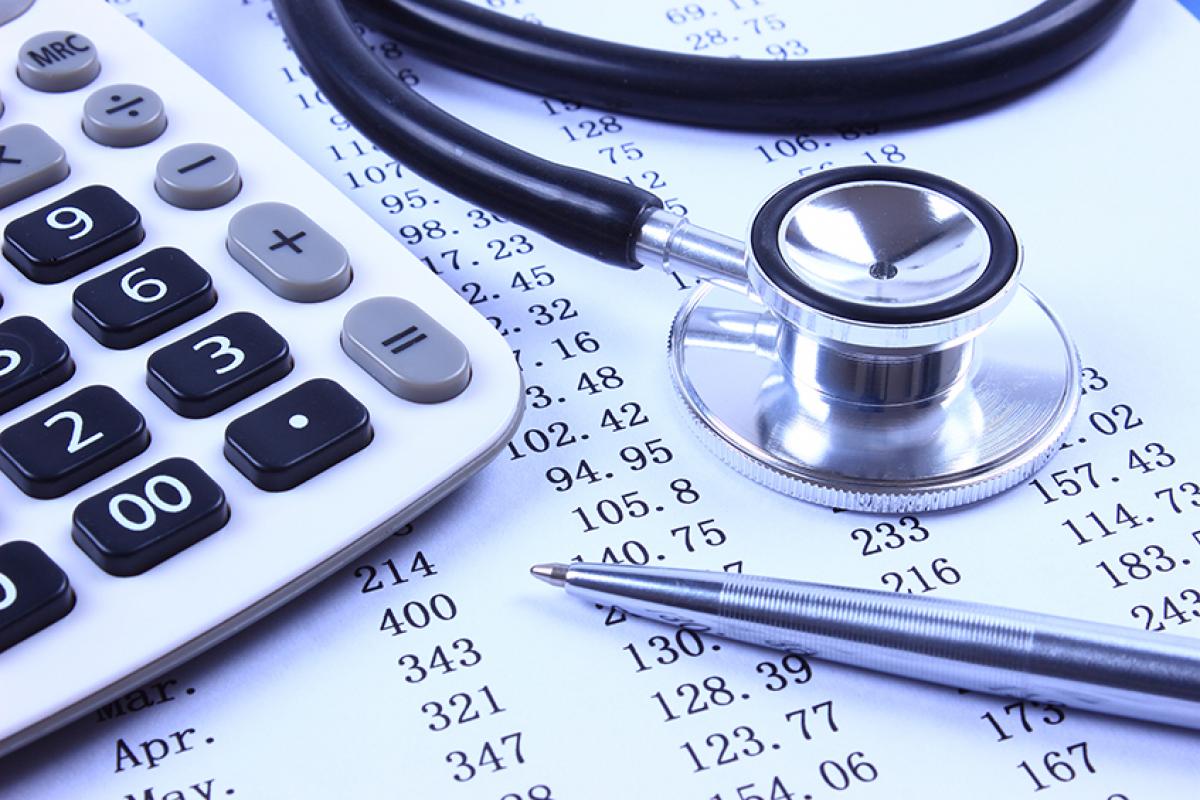 stock photo showing a calculator and a stethoscope on top of a balance sheet