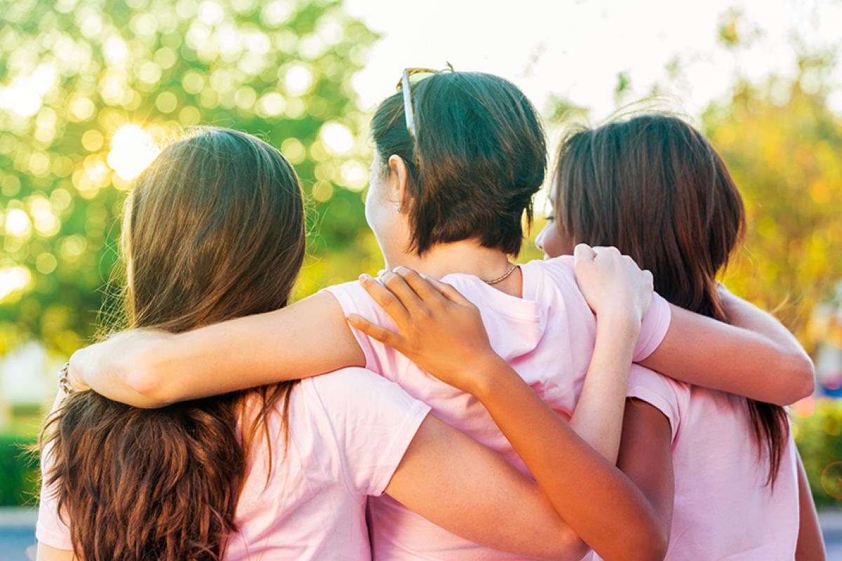 photo of the backs of three young women with their arms around each other