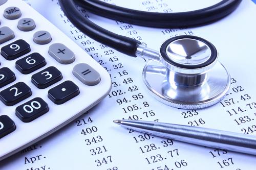 financial report with stethoscope, calculator, and pen